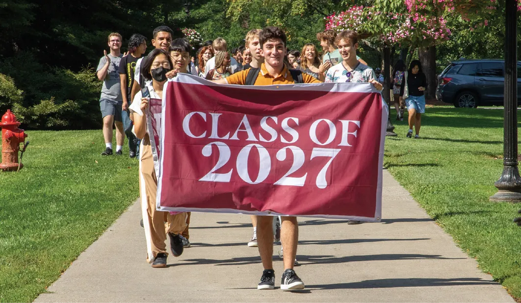 Class of 2027 students holding banner marching to first convocation