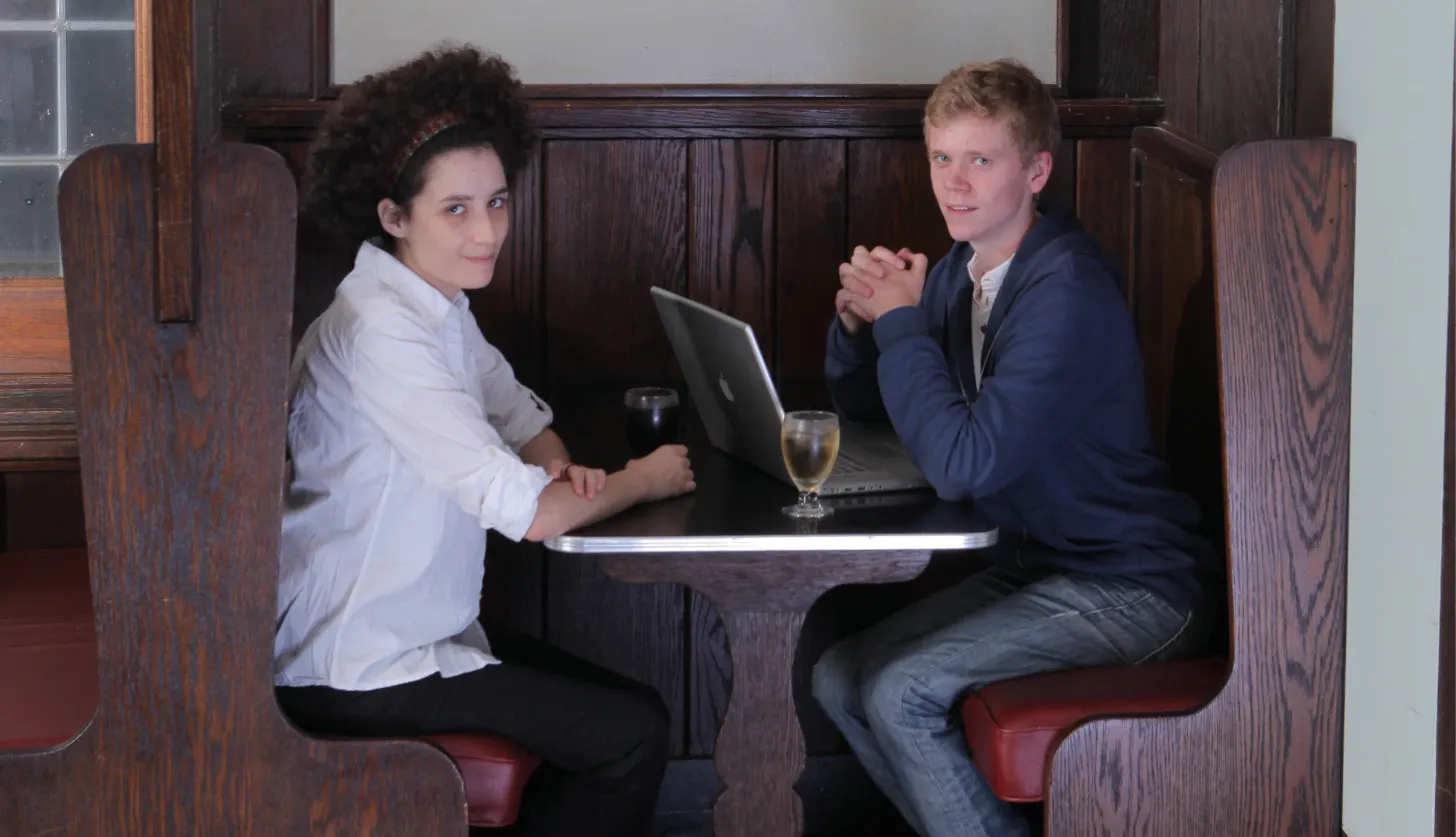 Two students in sitting in wood booth at the pub