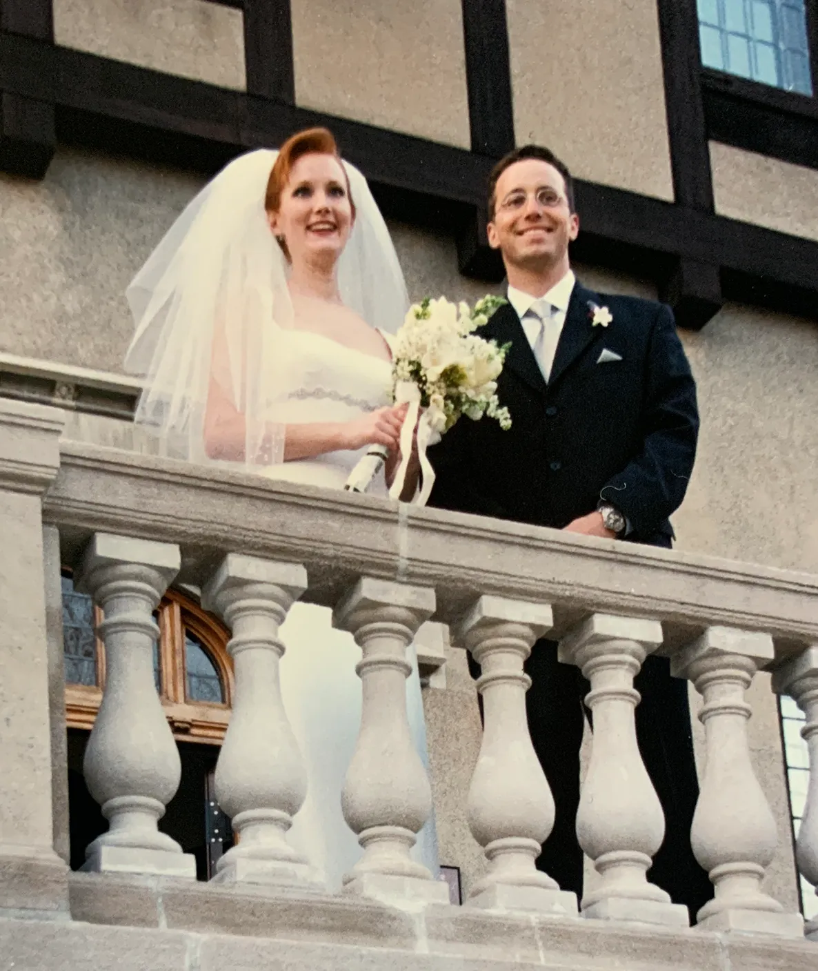 Matt Soper and Samantha Trautman Soper just married standing near railing of balcony