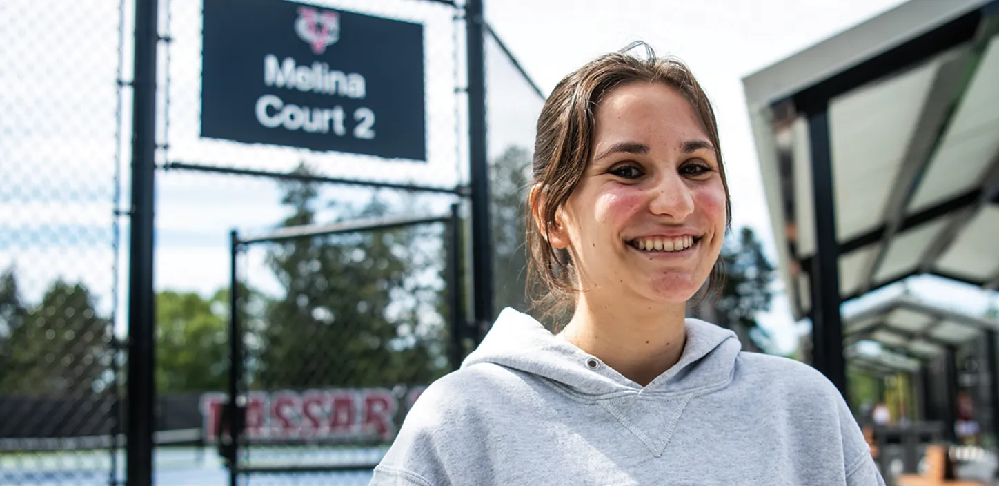 Melina Stavropoulos smiling in front of sign on court named after her