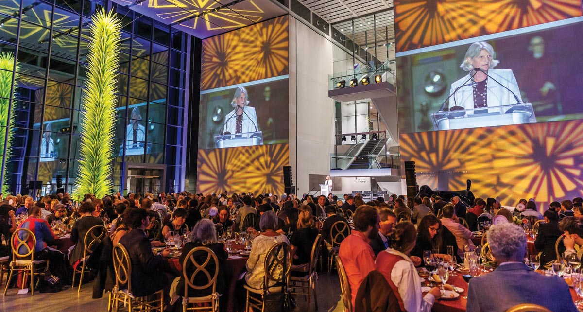 A room hosting a dinner in the Boston Museum is filled with alums amid colorful splashes of color on the walls.