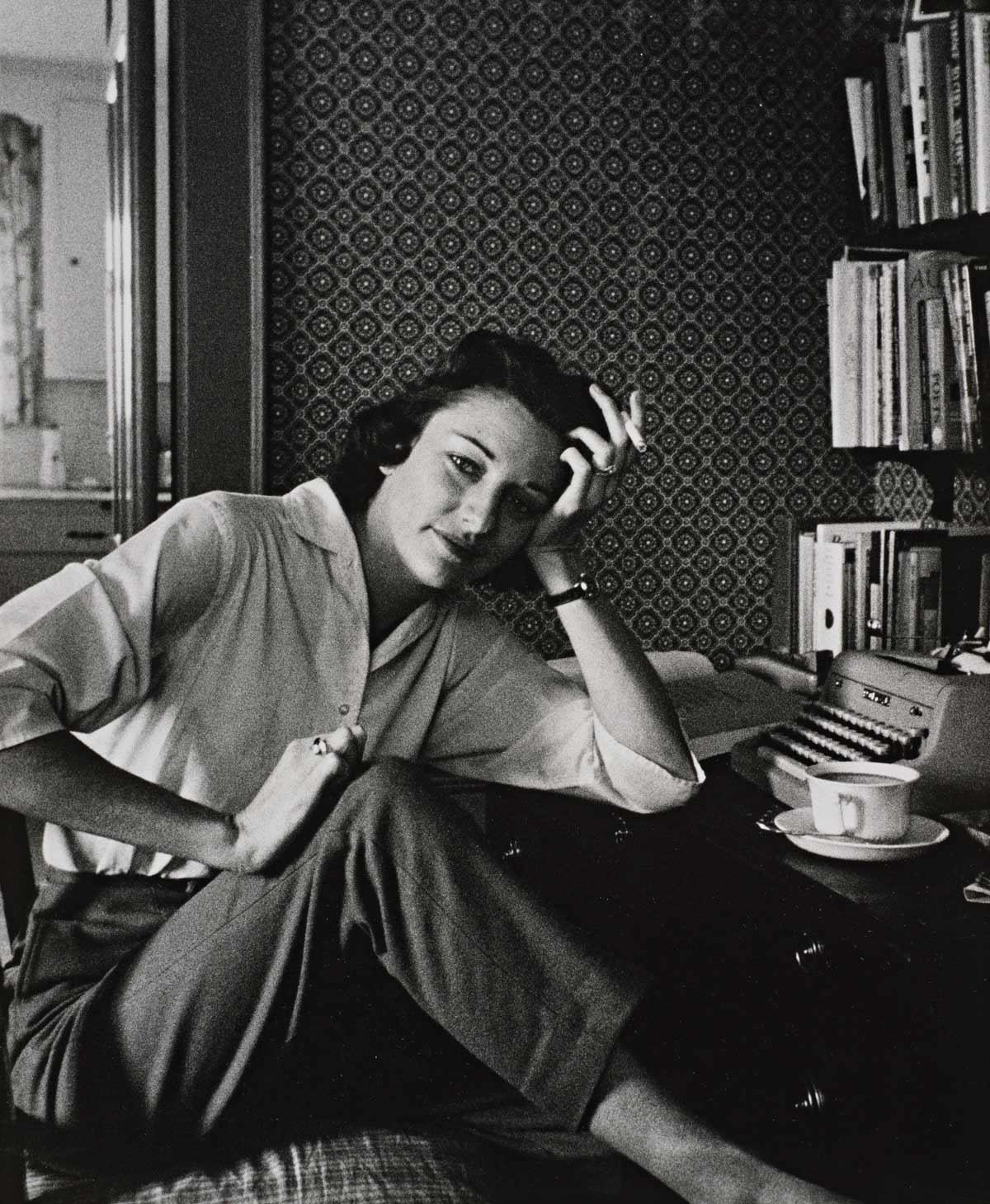 McKenna’s portrait of poet Anne Sexton, cigarette in hand, curled up in an office chair in front of a typewriter.