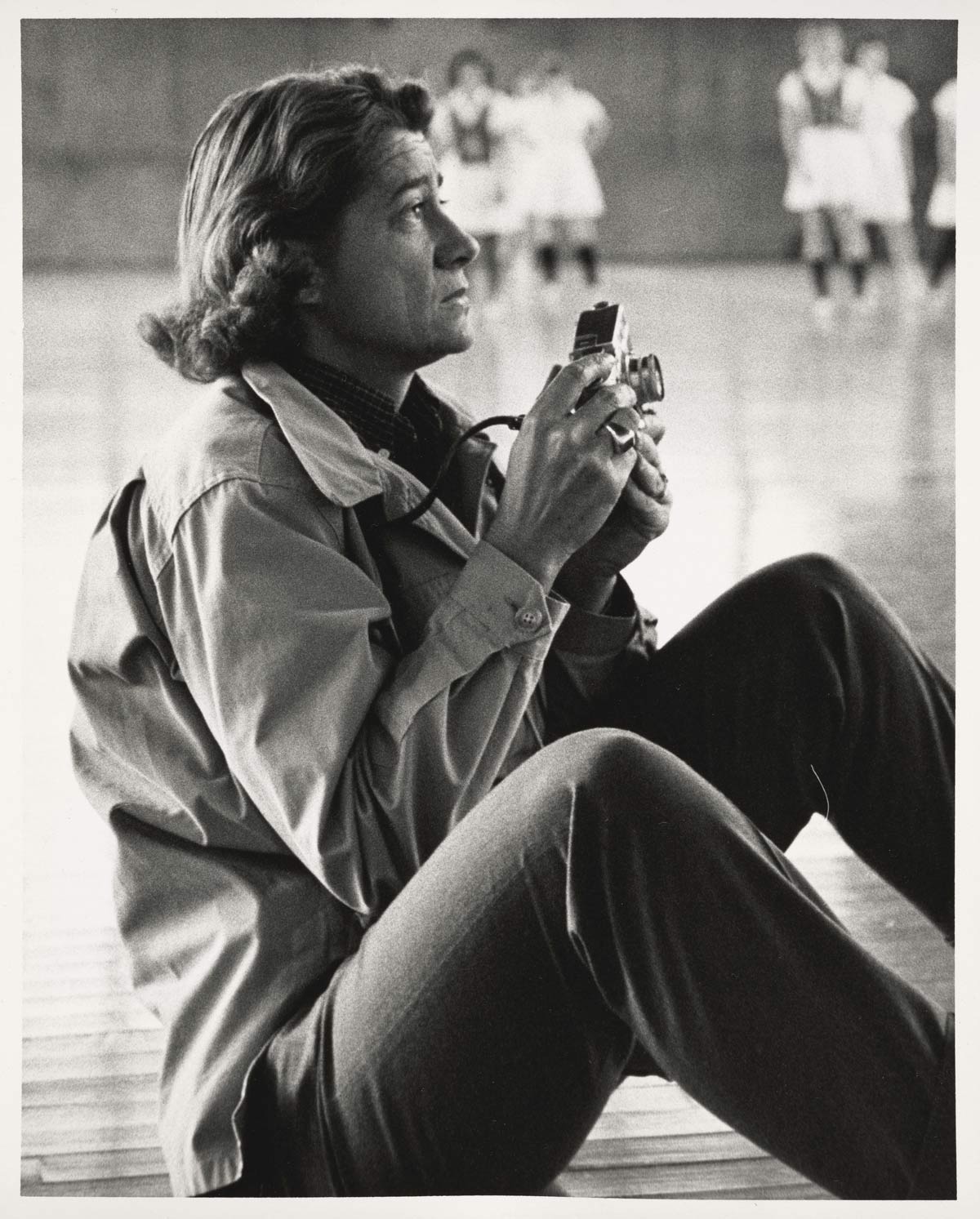Portrait of photographer Rollie McKenna, class of 1940, with a camera, at work at a gymnasium at Yale.