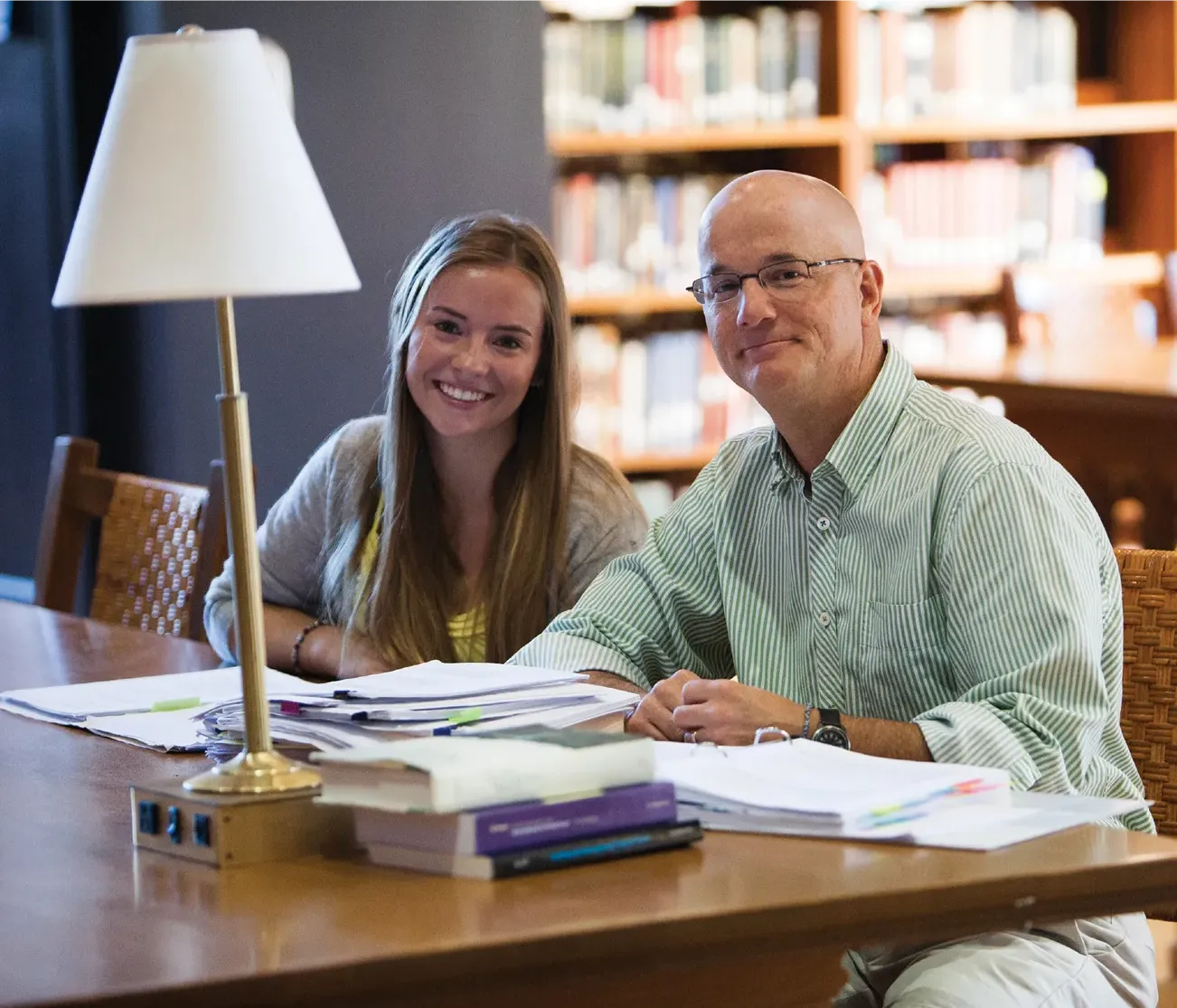 Hannah Van Demark, class of 2015, a Ford Scholar, and her faculty mentor, history professor Robert Brigham, sit at a table filled with books and papers in the Vassar Library.