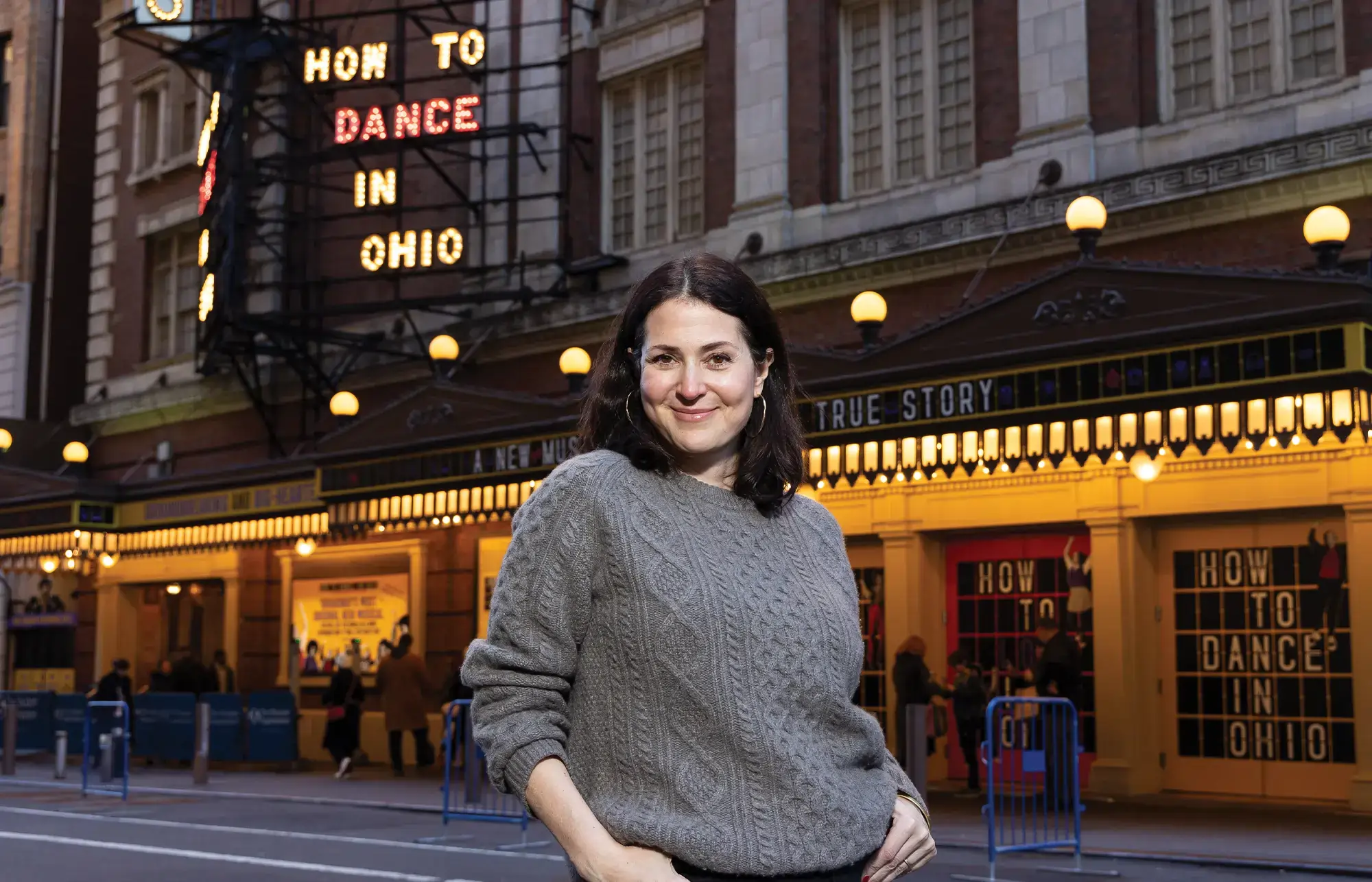 Alexandra Shiva, class of 1995, stands across from the marquee of How to Dance in Ohio, on Broadway in NYC.