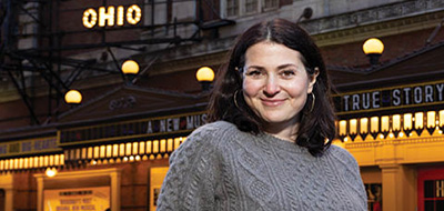Alexandra Shiva, class of 1995, stands across from the marquee of How to Dance in Ohio, on Broadway in NYC.