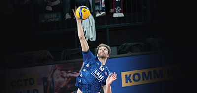 Professional volleyball player Matt Knigge, class of 2018, springs high in the air to hit a ball.