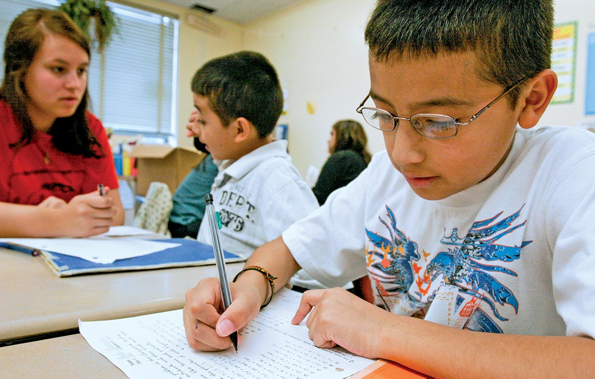 Vassar student helps younger children at a local school with writing.