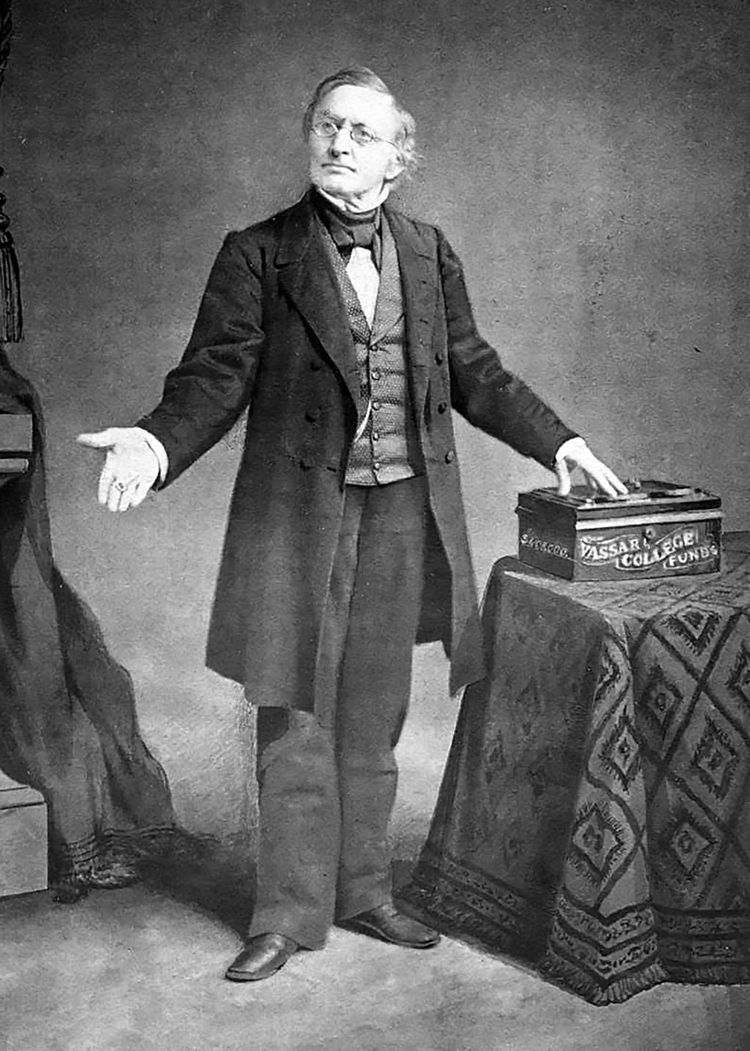 Black and white portrait of Matthew Vassar posing with a box labeled “Vassar College Funds”.