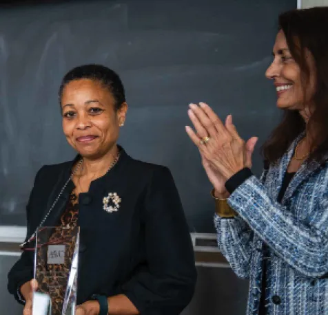 Pamela Harris ’92 stands in front of a black board holding her trophy for the Spirit of Vassar Award.