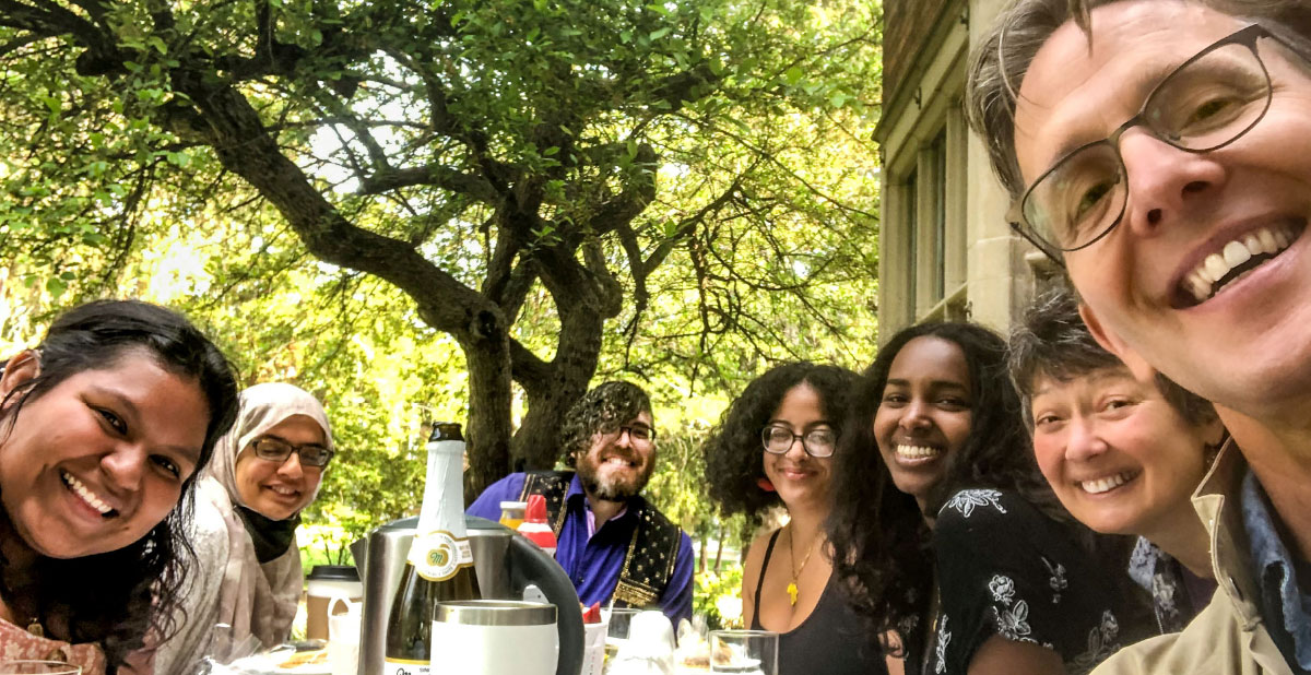 Several smiling people sit around a table before a bounty of food.