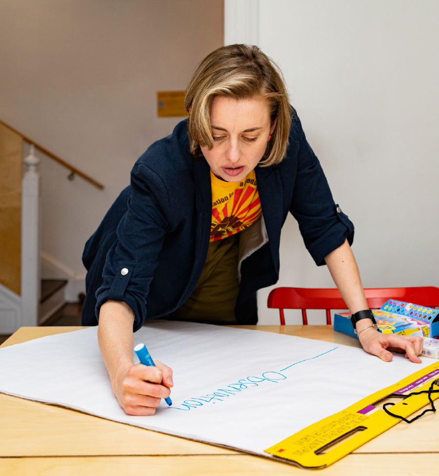 Amanda Munroe, Director of Restorative Practices, writes something on a large piece of poster paper.