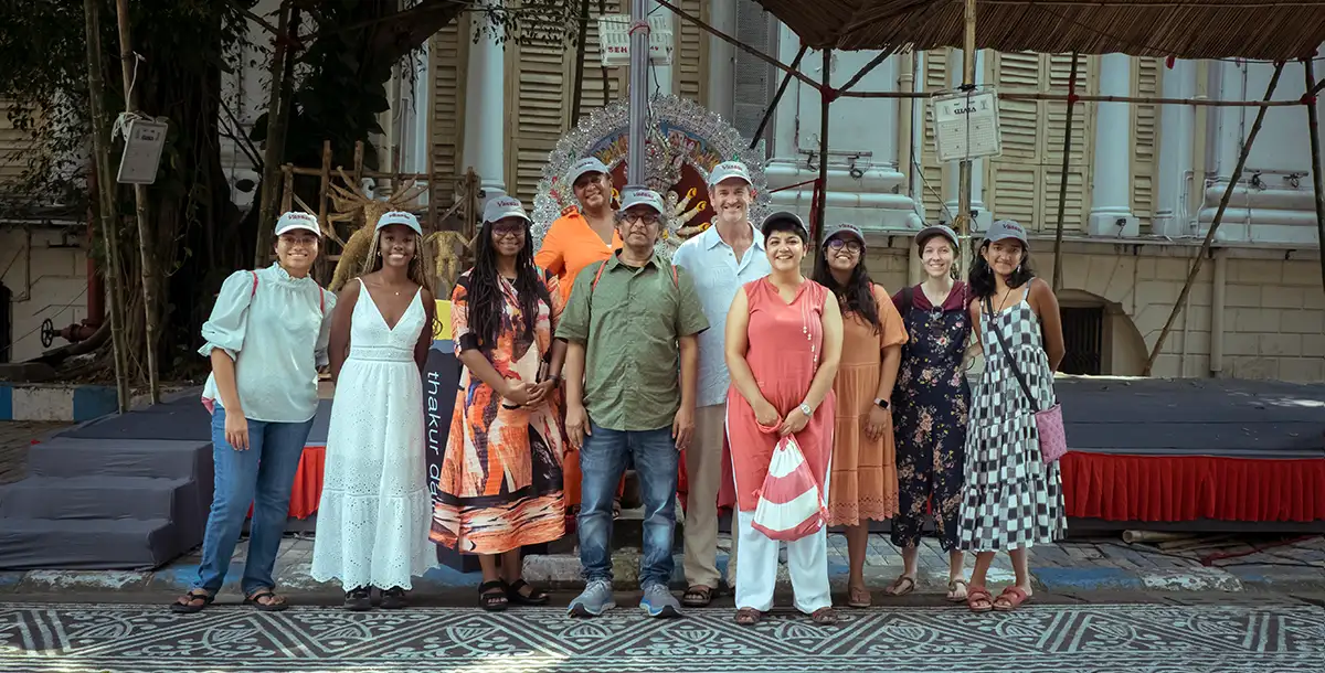 A small group of students and faculty stand in front of a building in India.