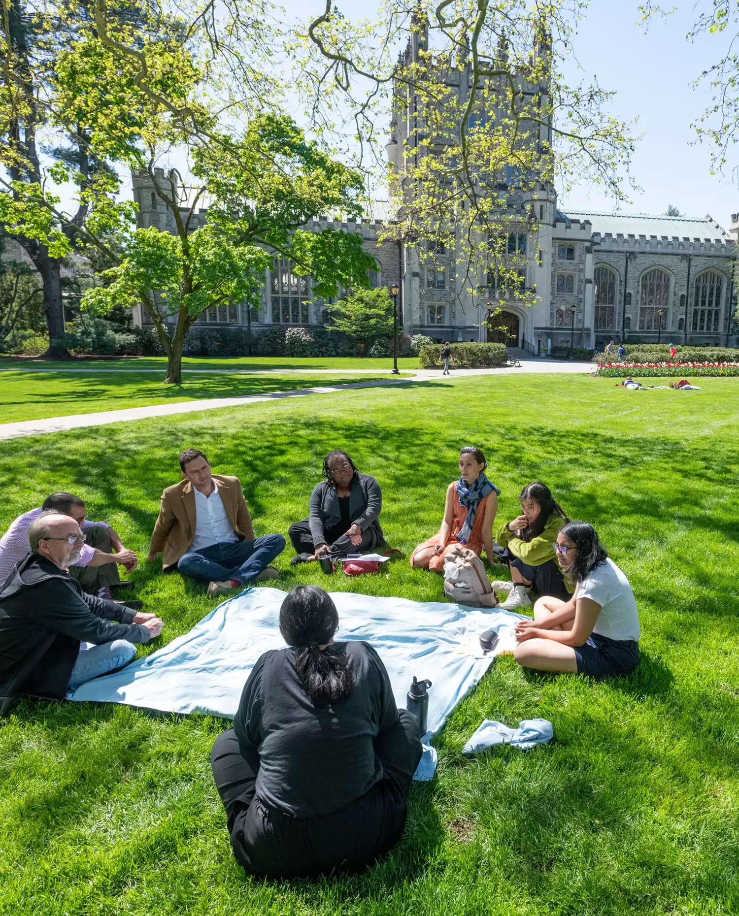 Vassar students and faculty sit around a blanket on the Library Lawn.