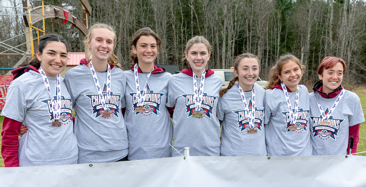 Vassar Track and Field team stands, arms linked, with gold medals around their necks after winning the Liberty League Championship.