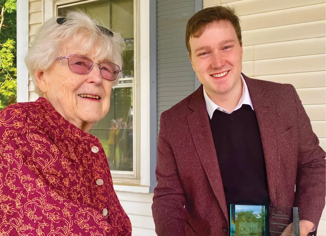 Portrait of Aidan Chisamore ‘24 receives an award from a woman.