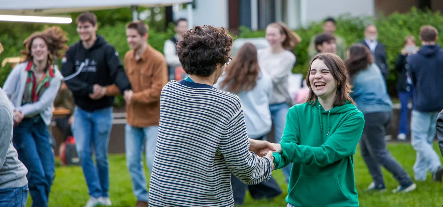 Two students hold hands while dancing.