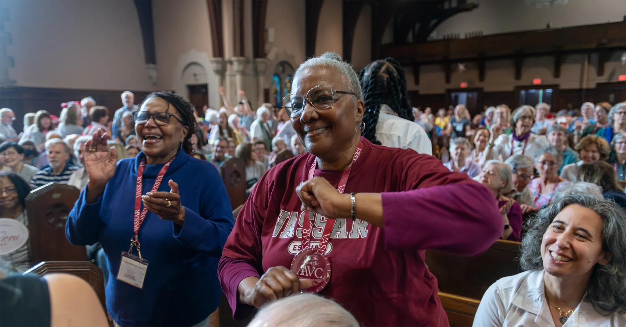 Two Vassar alums stand up and celebrate in the Chapel.