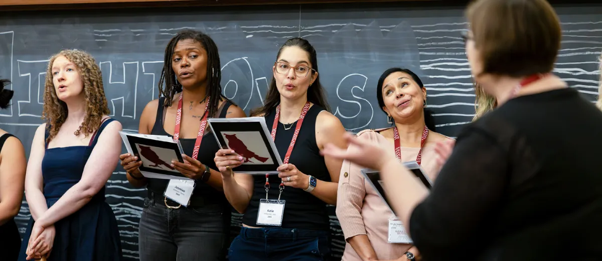 A group of former Night Owls sing in a row, while another woman conducts them.
