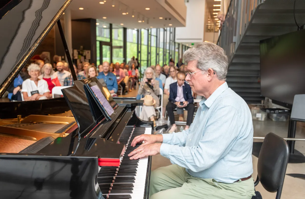 A Vassar alum plays piano for an audience.