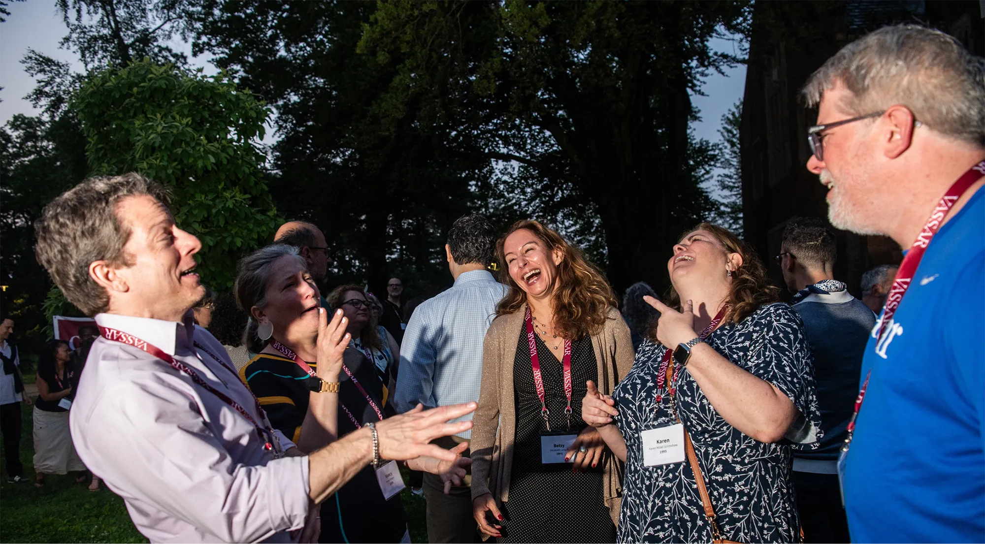 A group of alums talk and laugh outside on the Noyes Quad.