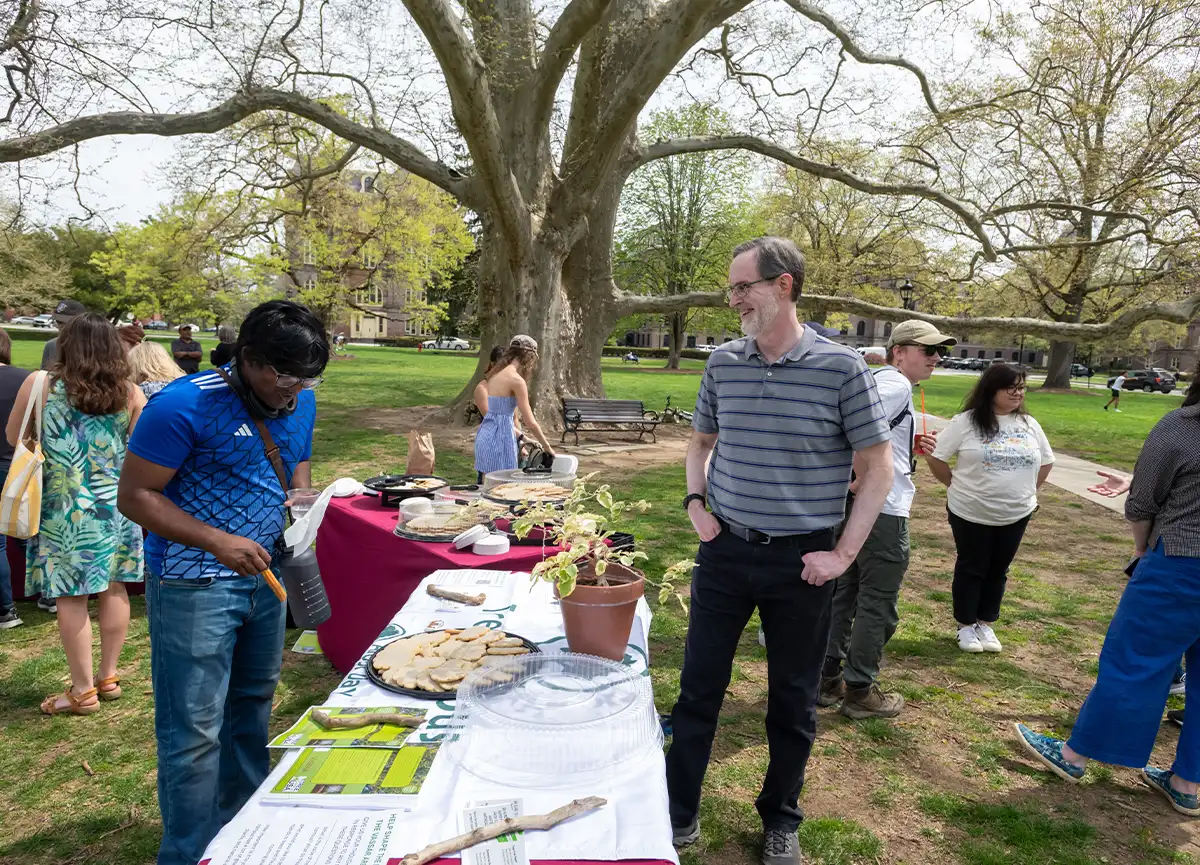 Members of the Vassar community gather at a table with tree-shaped cookies on the library lawn.