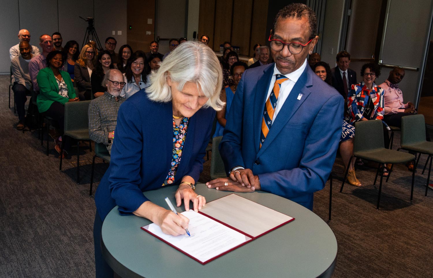 President Bradley signs a document as the President of SUNY-New Paltz looks on.