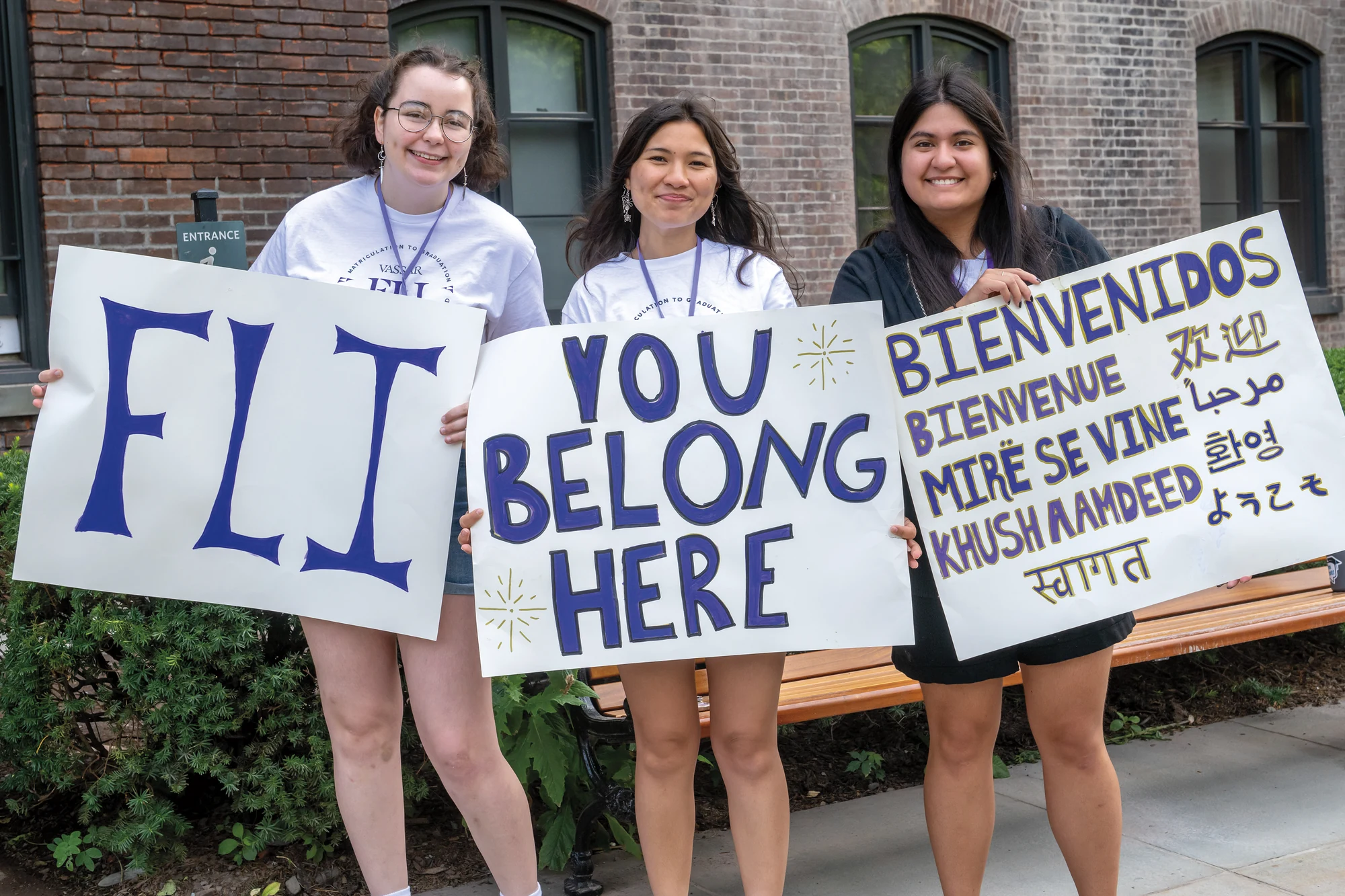 Three Vassar students hold signs welcoming first-generation and low-income students to the FLI community.