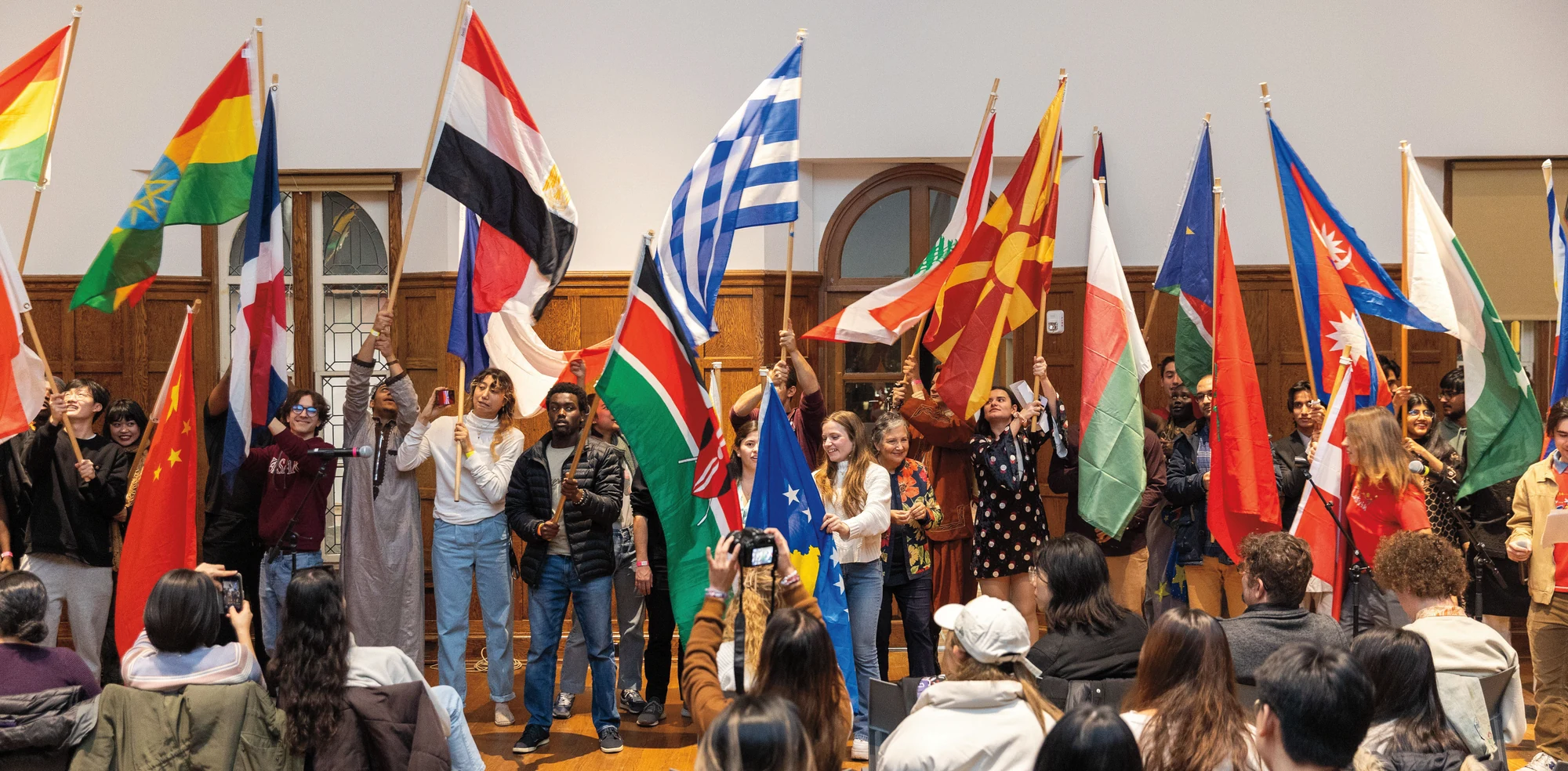 Students carry flags representing countries from around the world during a Vassar campus event.