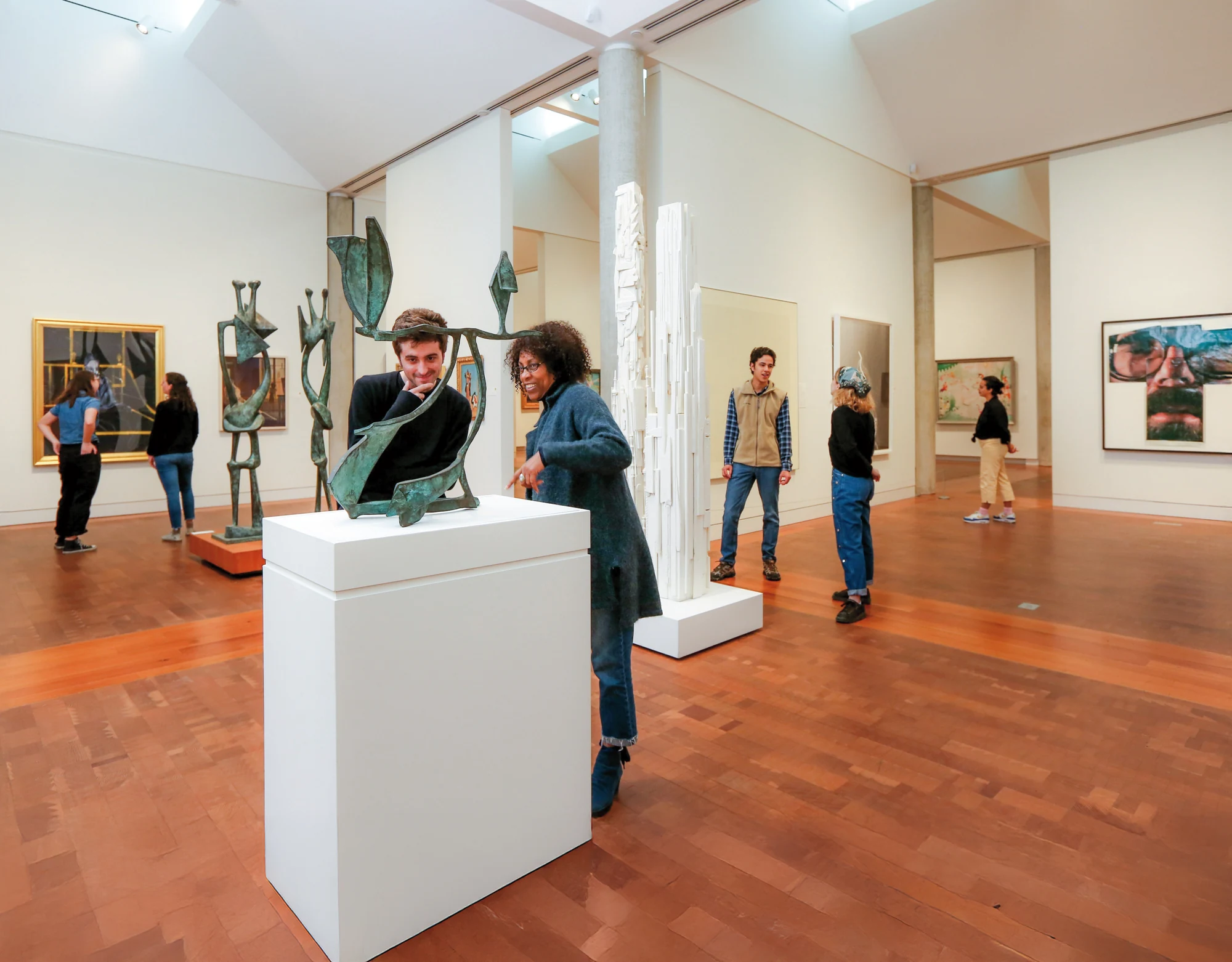 A group of people views artwork together inside a museum gallery.