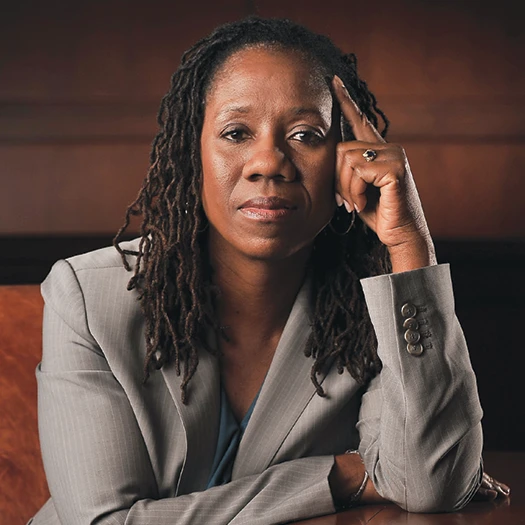 Sherrilyn Ifill rests one hand against her temple while seated in a gray suit.