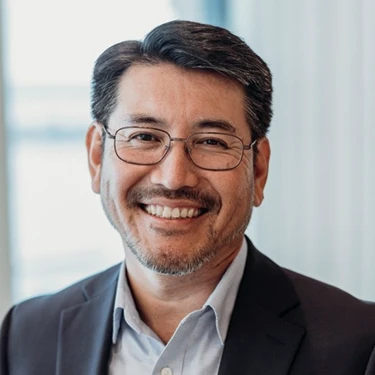 Seiji Hayashi smiles in a professional headshot, wearing glasses and a dark blazer.