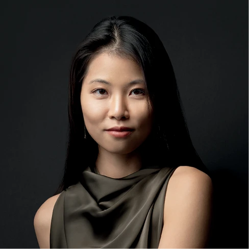 Kimberly Nguyen poses against a dark background in a sleeveless satin top.