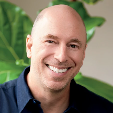 Michael Fanuele smiles in a headshot with green plants in the background.