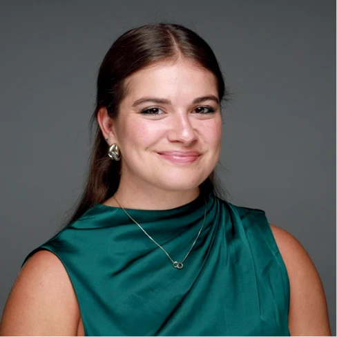 Lindsey Sample smiles in a green sleeveless top against a gray background.